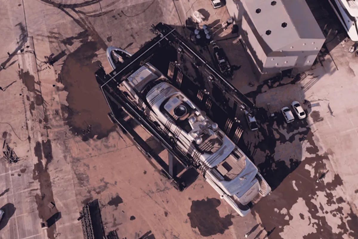 Overhead view of a yacht in a travel lift beside a covered yard building