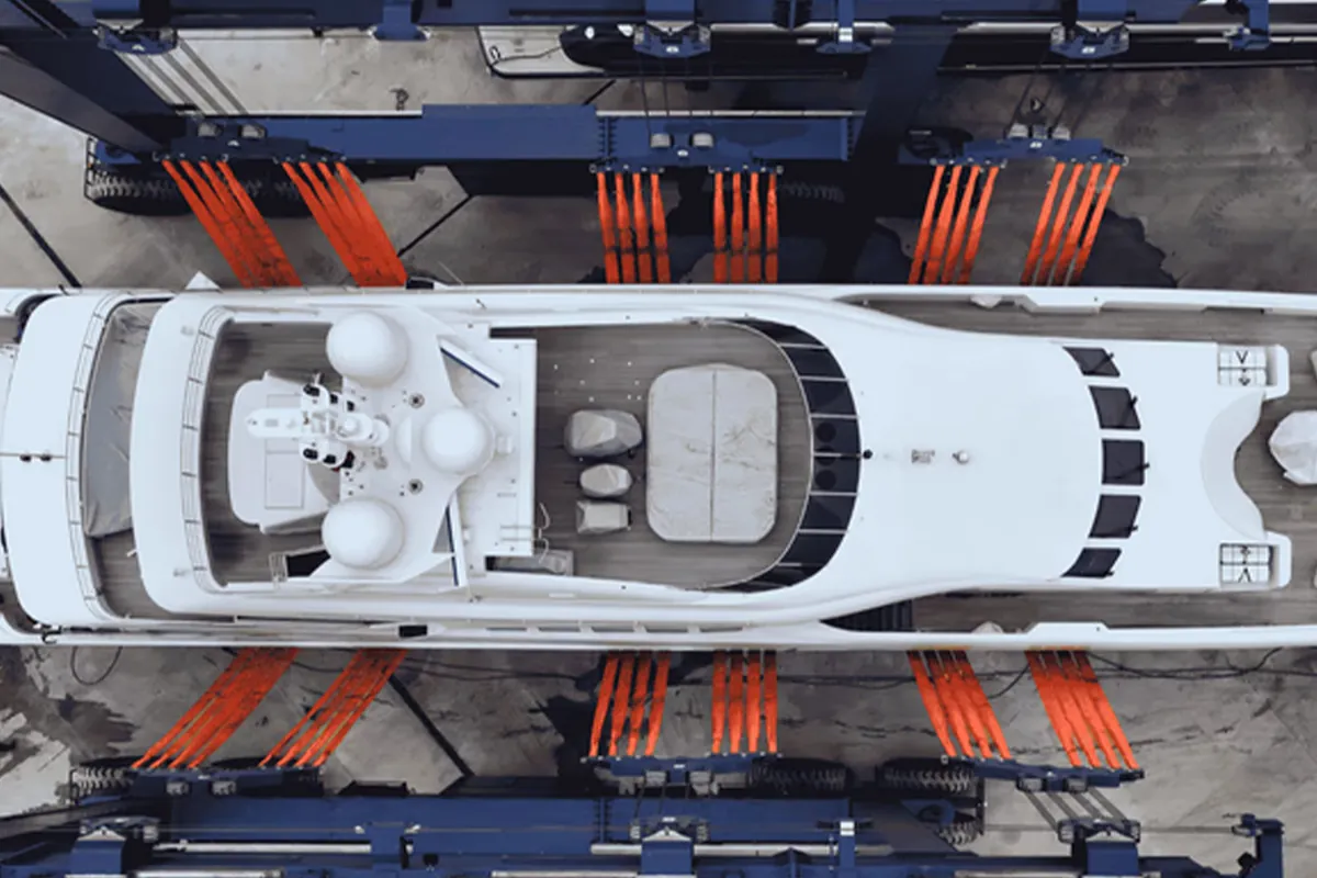 Motor yacht supported by orange travel-lift slings, seen from above