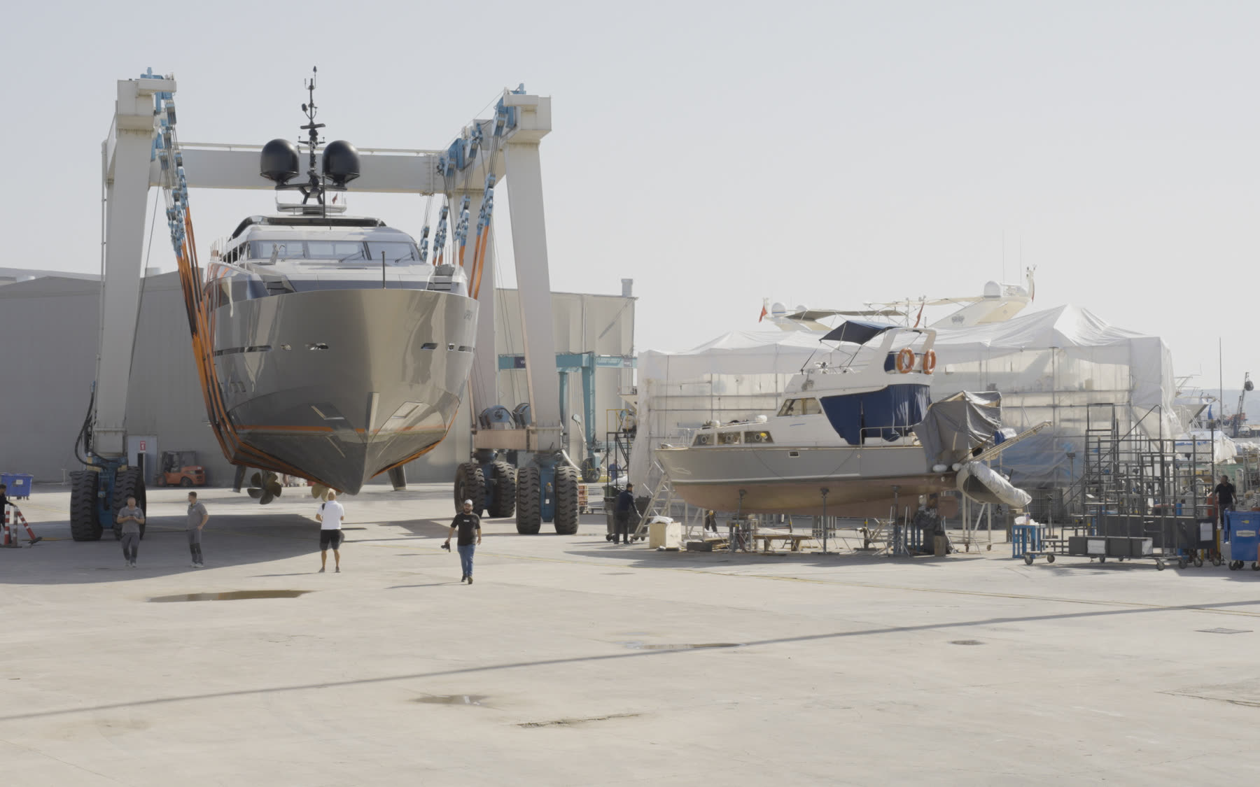 Travel lift and a second yacht ashore in an active yard